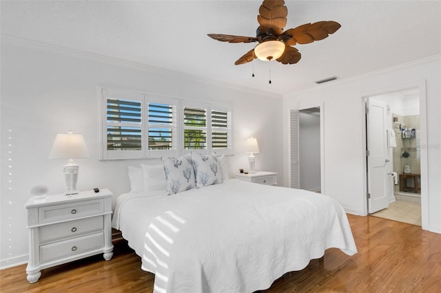 bedroom featuring ceiling fan, light hardwood / wood-style floors, crown molding, and connected bathroom