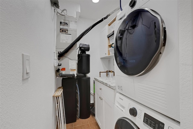 washroom featuring light tile patterned flooring, cabinets, and stacked washer / dryer