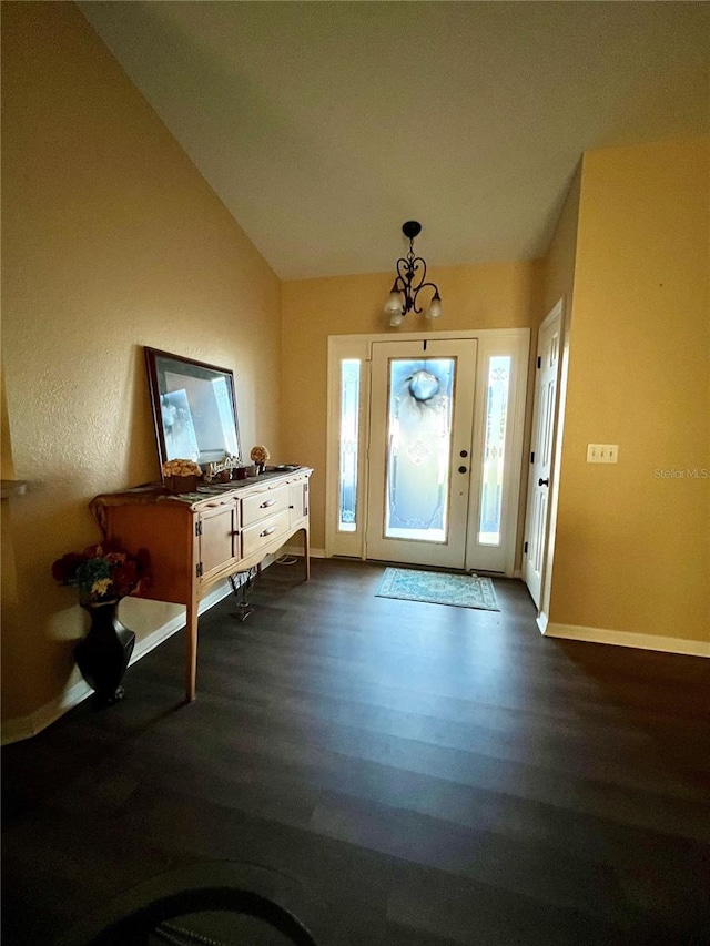 entryway with dark hardwood / wood-style flooring, lofted ceiling, and a chandelier