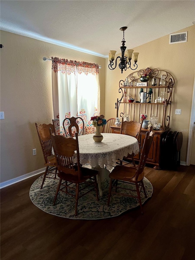 dining space with dark hardwood / wood-style flooring and an inviting chandelier