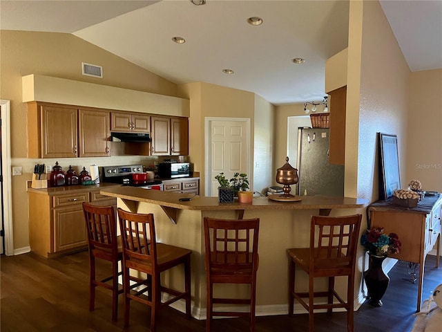 kitchen featuring a breakfast bar area, lofted ceiling, dark hardwood / wood-style floors, and appliances with stainless steel finishes