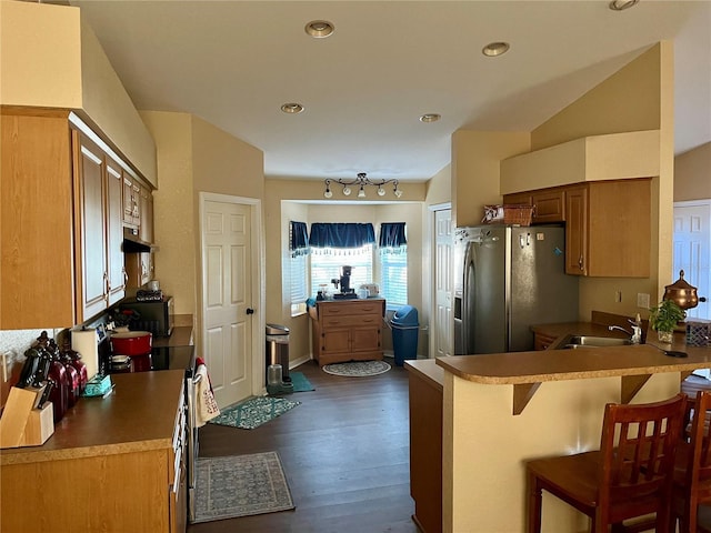 kitchen with a kitchen bar, stainless steel refrigerator with ice dispenser, dark wood-type flooring, sink, and range