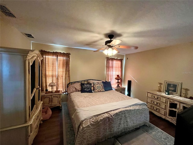 bedroom with a textured ceiling, ceiling fan, and dark wood-type flooring