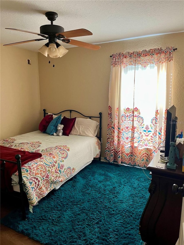 carpeted bedroom with a textured ceiling and ceiling fan