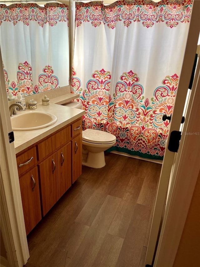 bathroom featuring wood-type flooring, vanity, toilet, and walk in shower