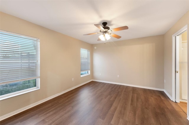 empty room featuring dark wood-style floors, a wealth of natural light, and baseboards