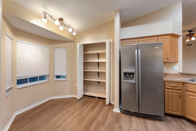 kitchen with baseboards, vaulted ceiling, light countertops, light wood-style floors, and stainless steel refrigerator with ice dispenser