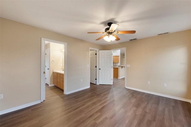 unfurnished bedroom with ensuite bathroom, dark wood-style flooring, visible vents, and baseboards