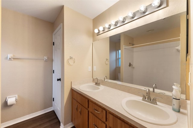 full bathroom featuring toilet, double vanity, a sink, and wood finished floors