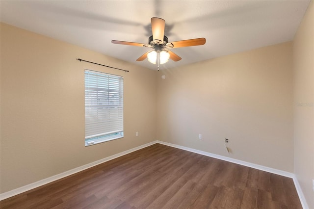 spare room with dark wood-type flooring, ceiling fan, and baseboards