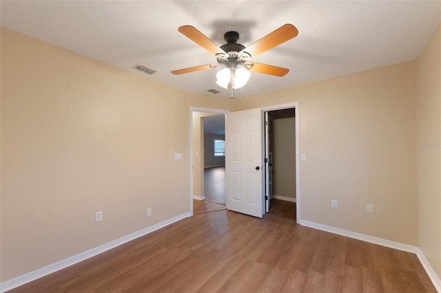 unfurnished bedroom featuring visible vents, ceiling fan, baseboards, and wood finished floors