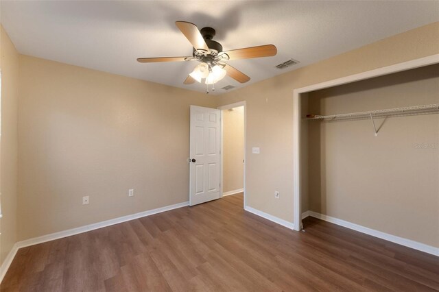 unfurnished bedroom featuring a closet, visible vents, ceiling fan, wood finished floors, and baseboards