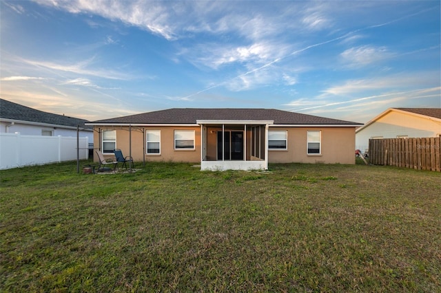 back of house featuring stucco siding, a fenced backyard, a sunroom, and a yard