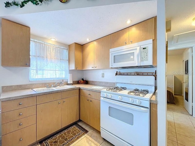 kitchen featuring a textured ceiling, sink, light tile patterned flooring, and white appliances