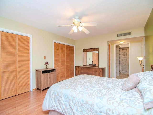 bedroom featuring ceiling fan, light wood-type flooring, and multiple closets