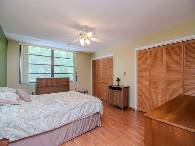 bedroom featuring ceiling fan, light hardwood / wood-style floors, and two closets