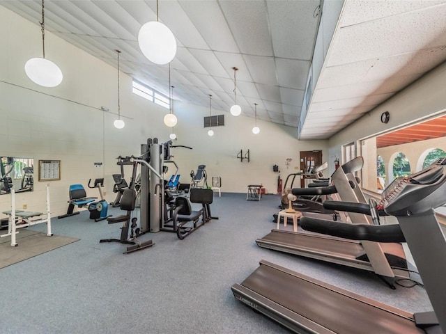 workout area with visible vents, a towering ceiling, and a drop ceiling