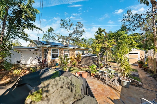 view of front of property featuring solar panels, a patio area, and a shed