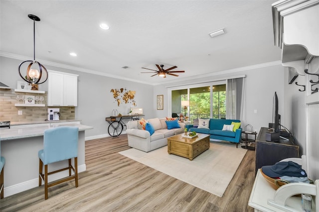 living room featuring ceiling fan, ornamental molding, and light hardwood / wood-style flooring