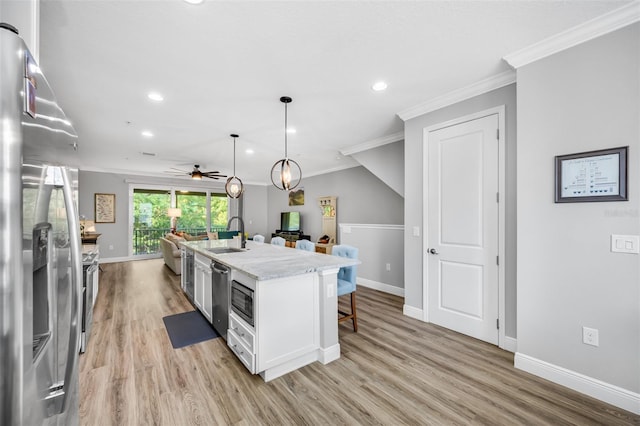 kitchen with pendant lighting, white cabinets, stainless steel fridge with ice dispenser, light hardwood / wood-style floors, and an island with sink