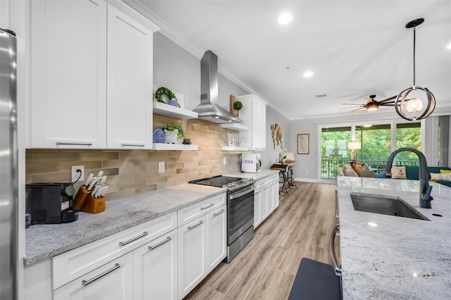 kitchen with appliances with stainless steel finishes, wall chimney exhaust hood, ceiling fan, sink, and white cabinetry