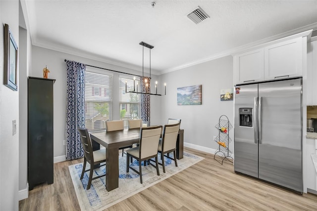 dining space featuring a textured ceiling, a chandelier, crown molding, and light hardwood / wood-style flooring