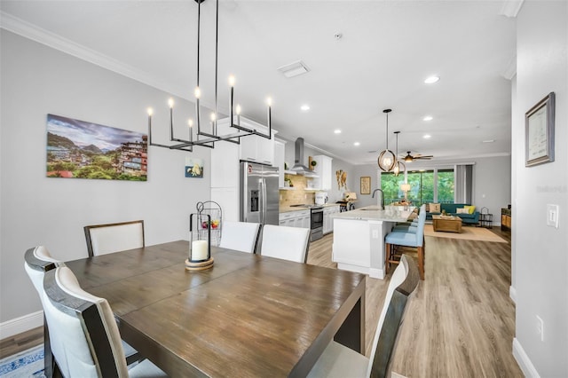 dining room featuring ceiling fan with notable chandelier, ornamental molding, and light hardwood / wood-style flooring