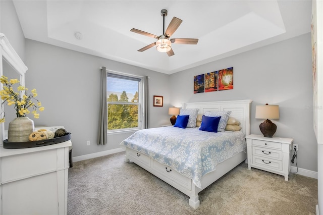 carpeted bedroom featuring a raised ceiling and ceiling fan