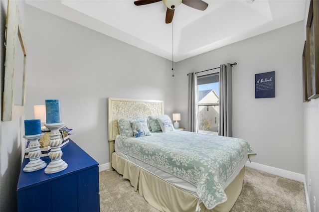 carpeted bedroom with ceiling fan and a raised ceiling