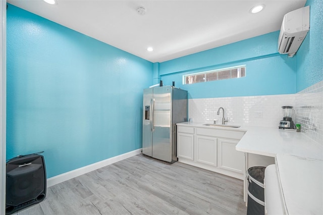 bathroom featuring wood-type flooring, backsplash, a wall unit AC, and sink