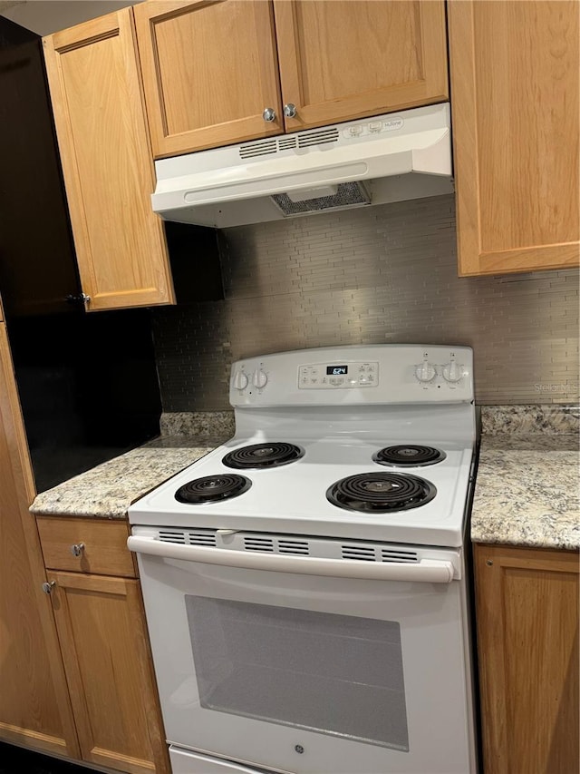 kitchen featuring light stone counters, white electric stove, and tasteful backsplash