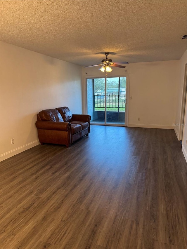 living room with a textured ceiling, ceiling fan, and dark hardwood / wood-style floors