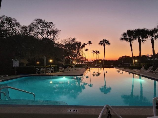 pool at dusk featuring a patio area