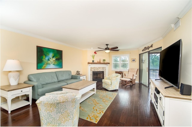 living room with a fireplace, dark hardwood / wood-style flooring, ceiling fan, and crown molding