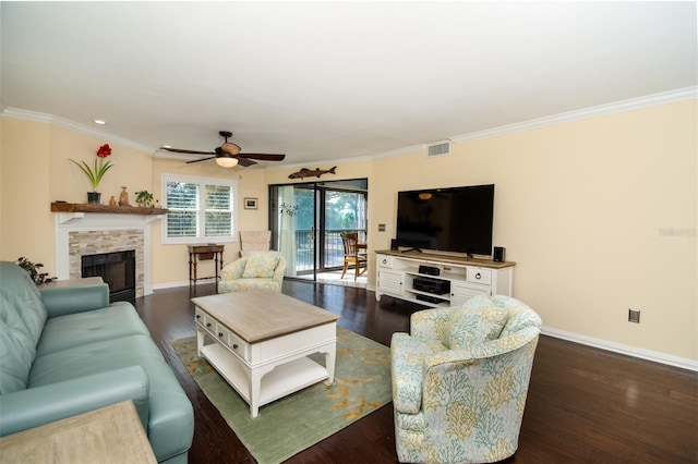 living room with a stone fireplace, ceiling fan, dark wood-type flooring, and ornamental molding