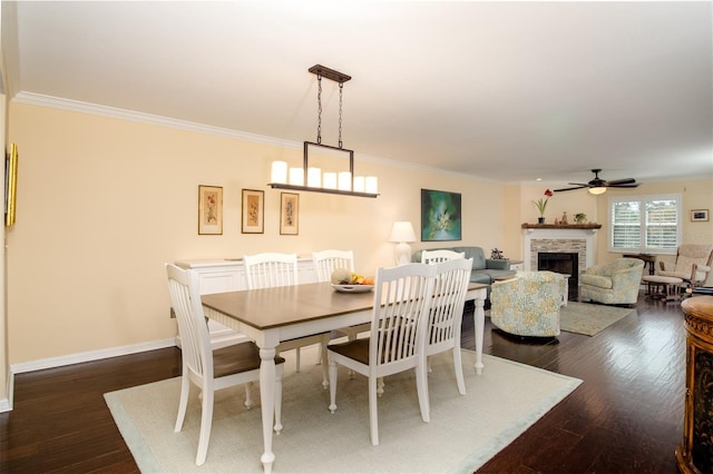 dining room with dark hardwood / wood-style floors, a stone fireplace, and crown molding