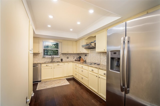 kitchen featuring a tray ceiling, sink, stainless steel appliances, and cream cabinetry