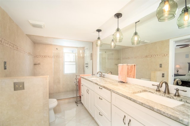 bathroom with ceiling fan, tile patterned floors, tiled shower, vanity, and tile walls