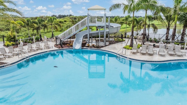 view of pool featuring a water view, a patio area, and a water slide