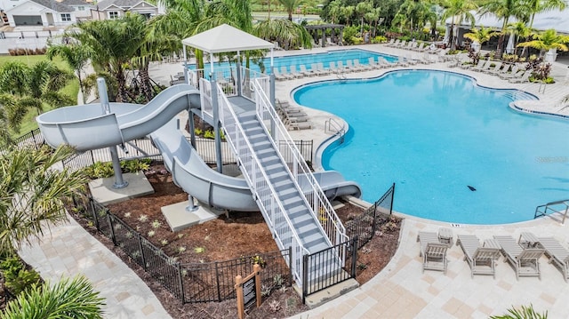 pool featuring playground community, a water slide, a patio area, and fence