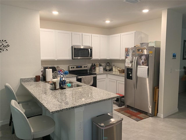 kitchen featuring a breakfast bar, a peninsula, white cabinetry, and stainless steel appliances