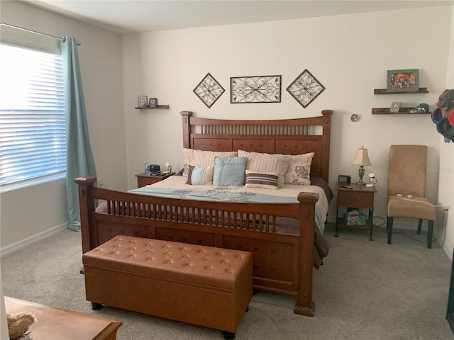 bedroom featuring light carpet, multiple windows, and baseboards