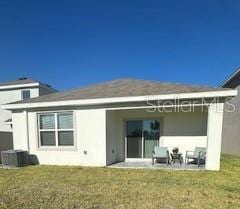 rear view of property with a yard, stucco siding, a patio area, and central air condition unit