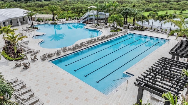 community pool featuring fence, a water slide, and a patio