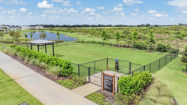 surrounding community featuring a lawn, a water view, fence, and a gate