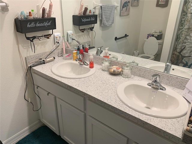 bathroom with double vanity, a sink, and toilet