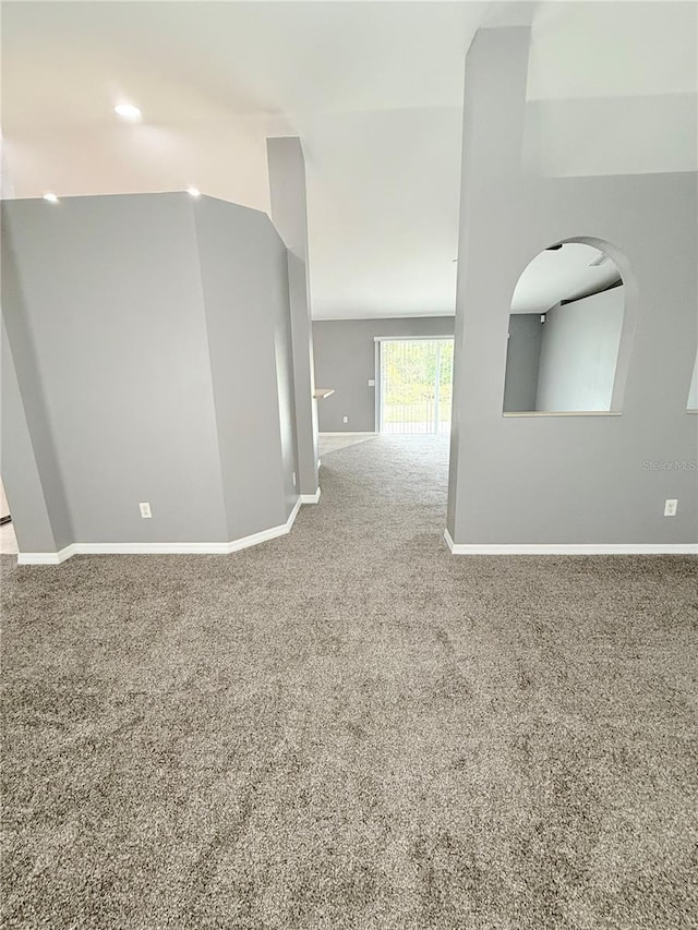 carpeted empty room with vaulted ceiling