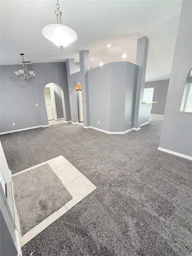 empty room with carpet flooring, vaulted ceiling, and an inviting chandelier