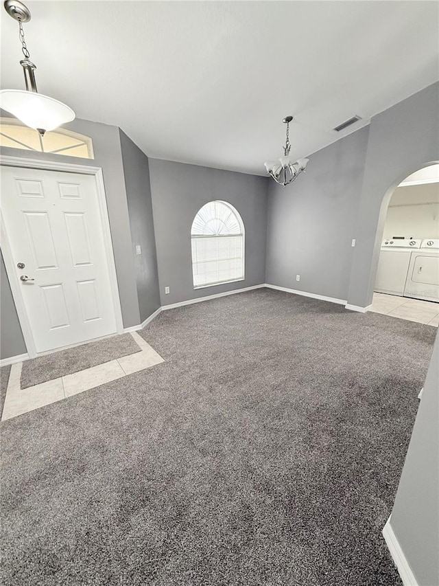 foyer with washer and clothes dryer, light carpet, and an inviting chandelier