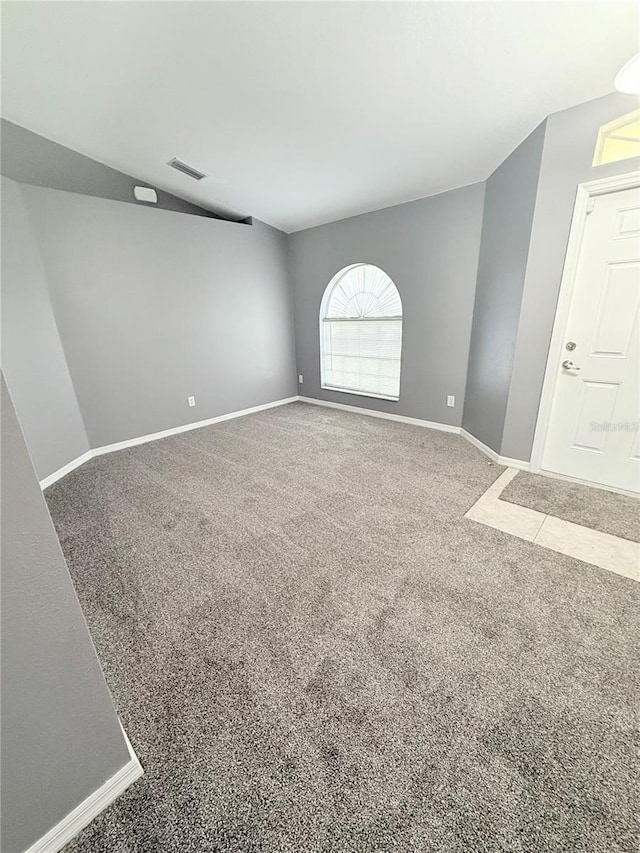 carpeted spare room featuring vaulted ceiling